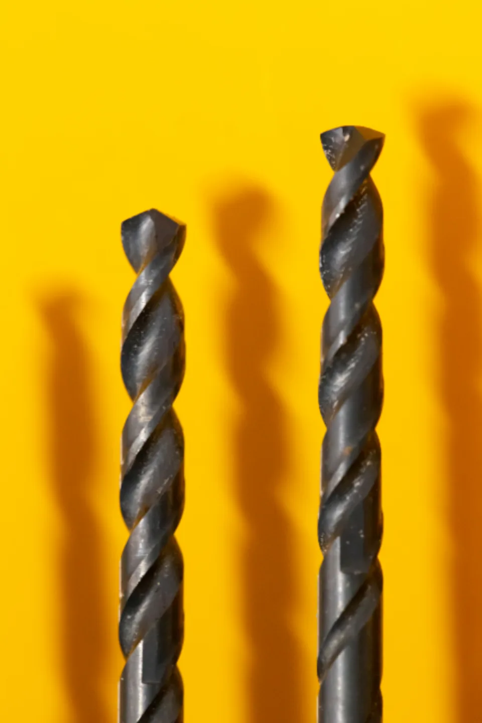 Two twist drills against a yellow ground